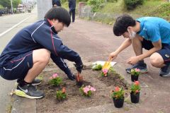 町道沿いの花壇に花を植える生徒