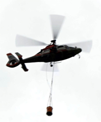 バケットをつるして上空３００メートルまで上昇するヘリコプター（須貝拓也撮影）