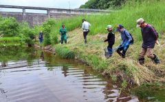 ダム川でウチダザリガニを釣る参加者ら（中札内の自然を愛する会提供）