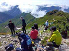 昨年、平取町山岳会が実施した町民向け登山ツアーで、幌尻岳山頂に腰を下ろし眺望を楽しむ参加者ら