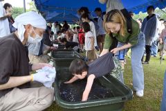 ニジマスのつかみ取りに熱中する親子