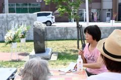 帯広空襲の碑の横で高橋キソさんの証言を語る浅見さん