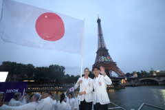 開会式でセーヌ川を進む船上で、エッフェル塔を背に日の丸を振る日本選手団旗手の江村美咲と半井重幸（右）＝２６日、パリ（ＡＦＰ時事）