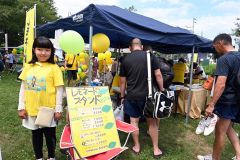 製作した看板の横に立つ飯田さん