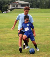 ゲーム形式の練習で福西さんと笑顔で競り合う小学生