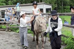 スタッフに支えられ乗馬体験を楽しむ園児たち