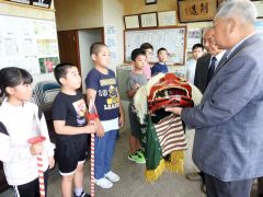 上川部長（左から３人目）に獅子頭を手渡す水澤会長（右）