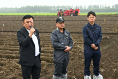 じゃがいも畑の前であいさつをする（左から）田崎一也社長、橋詰仁組合長、杉浦大斗幕別支所長（５日、午前１０時ごろ、帯広市以平町で。金野和彦撮影）