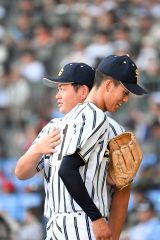 【夏の甲子園大会１回戦・白樺学園－創成館】１回のピンチを切り抜けてベンチに引き上がる半澤理玖投手（手前）を亀田直紀監督が肩をたたいてねぎらう（８月１１日、須貝拓也撮影）