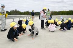 整備中の歴舟川橋の路面部分に落書きをする大樹小の児童