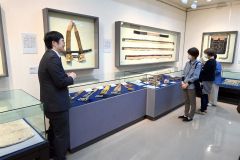 大和田さん（左）の解説を聞きながら展示資料を見る内覧会参加者