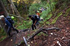 溶岩が積み重なった急な登山道を登る参加者ら