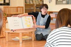 大型絵本「くだものどうぞ」を親子に読み聞かせする主任補の永原さん