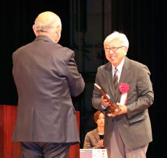 岡田会長（左）から記念の盾を受ける山田さん（右）