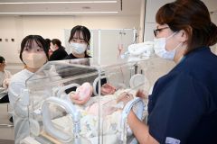 看護師から保育器内の新生児へのケアを学ぶ中学生ら
