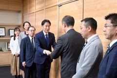 冨原議長（右から３人目）に条例案を手渡す清水道議（同４人目）