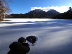 雌阿寒岳とアイスバブルをカメラに収める人