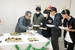 クリスマスにちなんだ姿で料理を取り分ける学生たち