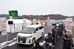 渡り初めで通行する関係車両（２２日午後０時２５分ごろ。金野和彦撮影）