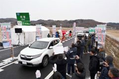 渡り初めで通行する関係車両（２２日午後０時２５分ごろ。金野和彦撮影）