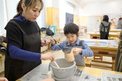 自作した素焼きの器に色付けする参加者