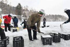 シャーベット状の雪をコンテナに詰め込む作業