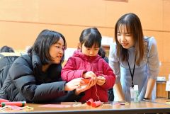 旧正月の飾り付けを制作する親子と見守るミーさん（右）