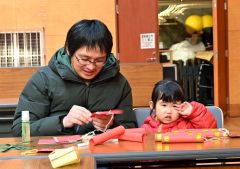 旧正月の飾り付けを制作する親子