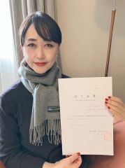 修了証書（認定証）を手に笑顔を見せる杉本さん