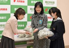 帯広北高ボランティア局の生徒とリングプルを畑中会長に手渡す大矢会長（中央）