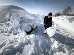 雪に埋まった車を掘り出す空港駐車上利用者（５日午前１０時半ごろ））