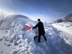 雪に埋まった車を掘り出す空港駐車上利用者（５日午前１０時半ごろ））
