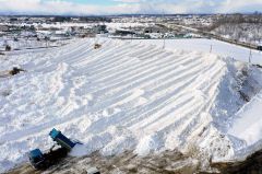 ダンプカーにより運び込まれた雪で大きな山となった雪捨て場（６日、幕別町依田で、塩原真撮影）