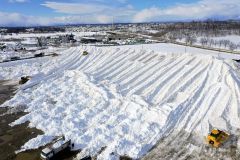 ダンプカーにより運び込まれた雪で大きな山となった雪捨て場（６日、幕別町依田で、塩原真撮影）