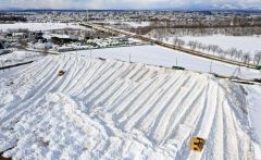 ダンプカーにより運び込まれた雪で大きな山となった雪捨て場（６日、幕別町依田で、塩原真撮影）