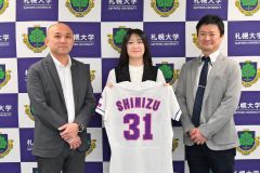 札大女子硬式野球部のユニホームを持つ手塚汐音マネジャー（中央）。戸出直樹監督（左）、清水祐太部長