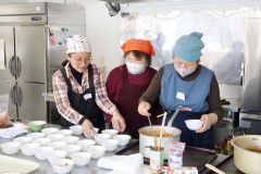 アシナさん（左）と「白いんげん豆のココナッツミルク煮」作りに挑戦する参加者ら