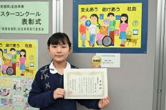 作品の前で賞状を手に笑顔を見せる森田さん