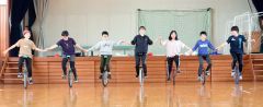 白木さん（中央）と横一線に並んで一輪車に乗る６年生ら