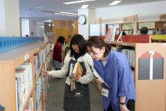 足立係長（右）と配架業務をする児童