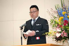 閉校記念式典であいさつする新津良明閉校記念事業協賛会長