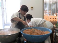 茹で上がった大豆を鍋から取り出す会員