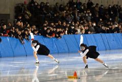 卒業式を終え、イベントに参加した帯三条高スケート部。制服姿で１００メートルを滑走する奥秋静子さん（右）と熊谷しゅうさん（金野和彦撮影）