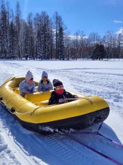 スノーモービルが引っ張るゴムボートで雪の上を疾走した子どもたち