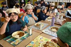 「音更高校　濃厚バターチキンカレー」をおいしそうに食べる児童ら（音更小）