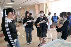 在校生（右）から乳児の抱き方を学ぶ高校生