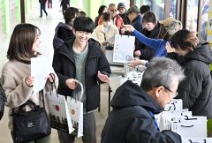 プレゼントを受け取り笑顔の来場者(16日正午ごろ、塩原真撮影)