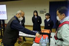 生徒と共に災害時の備蓄品を確認する町民