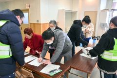避難所で「避難者受付管理簿」に必要事項を書き込む住民ら