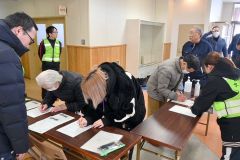 避難所で「避難者受付管理簿」に必要事項を書き込む住民ら